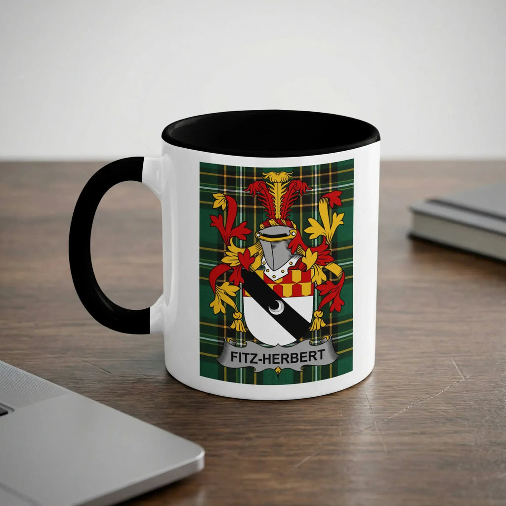 Mug with Fitz-Herbert family crest on wood desk beside laptop.