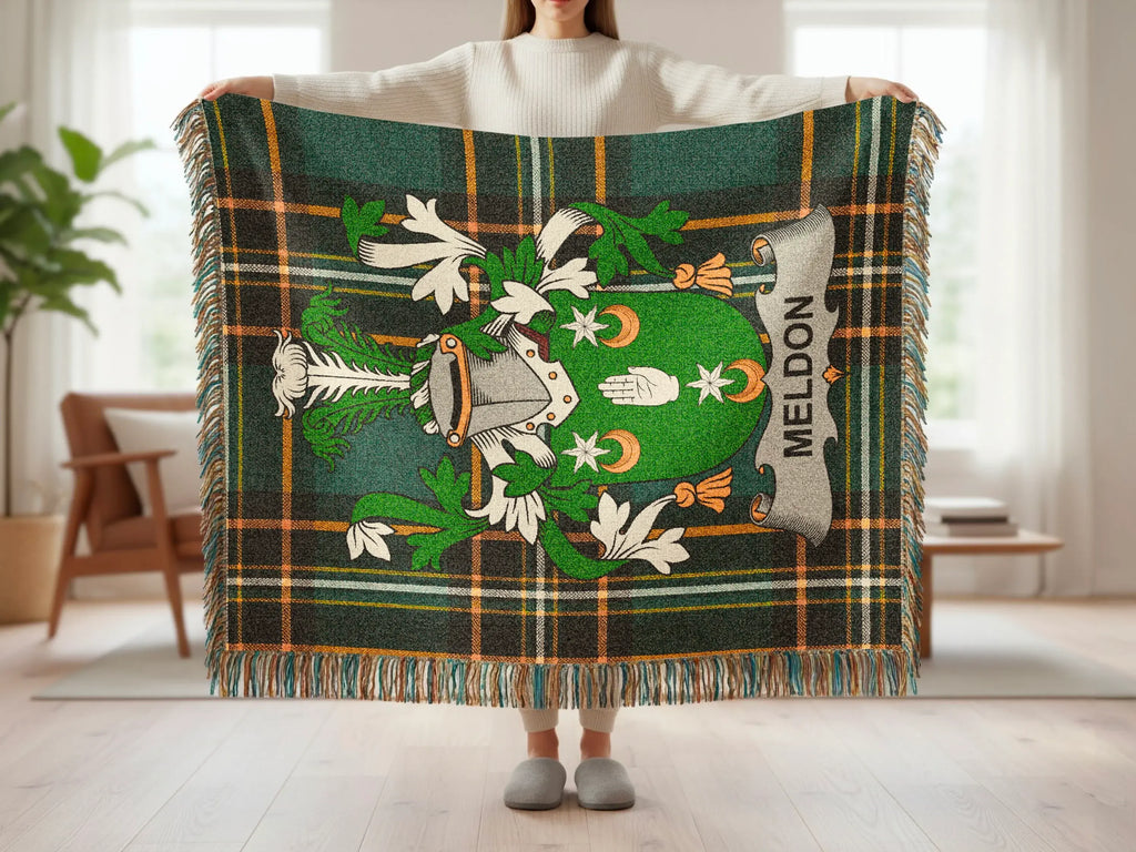 Green tartan blanket with family crest featuring shield, helmet, and "MELDON" banner.