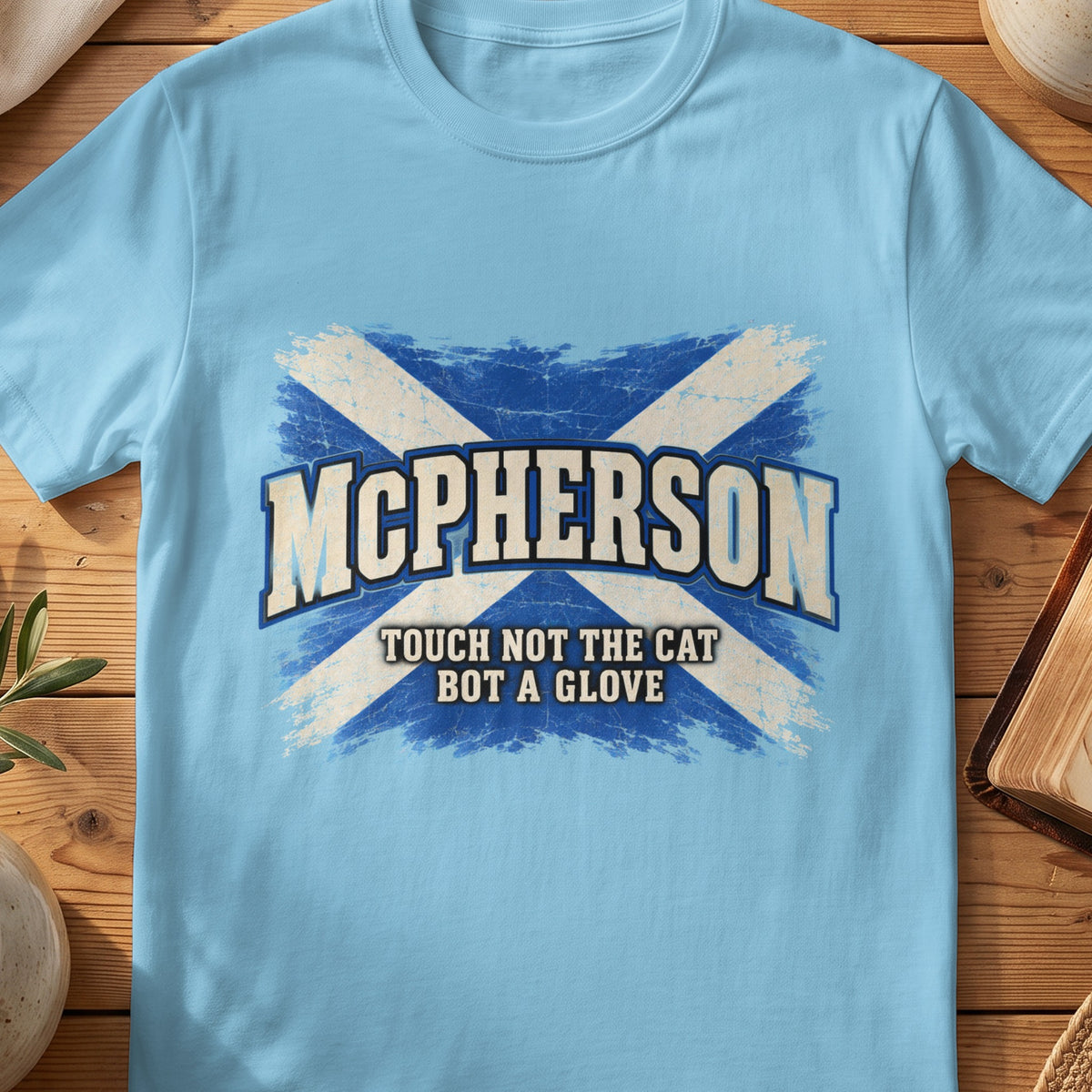 McPherson Scottish Saltire T-shirt in Sky, with distressed blue and cream flag and “Touch Not the Cat Bot a Glove” lettering.