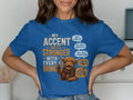 Blue t-shirt with Highland cow graphic and text about accents and drinks.