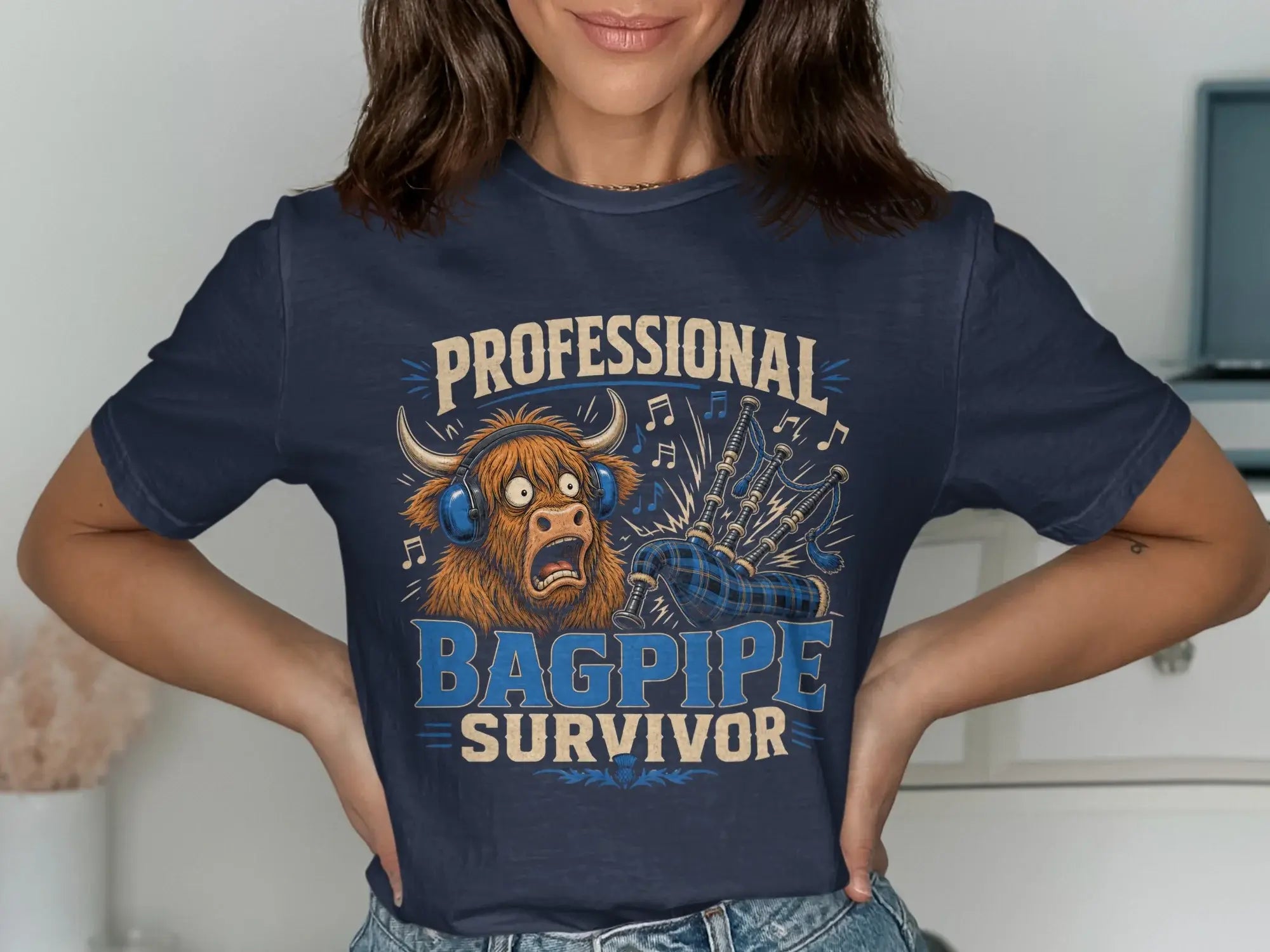 Navy t-shirt with a surprised Highland cow wearing headphones, playing bagpipes.