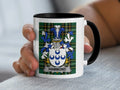 White mug with black rim, featuring the Hammond family crest on plaid background.