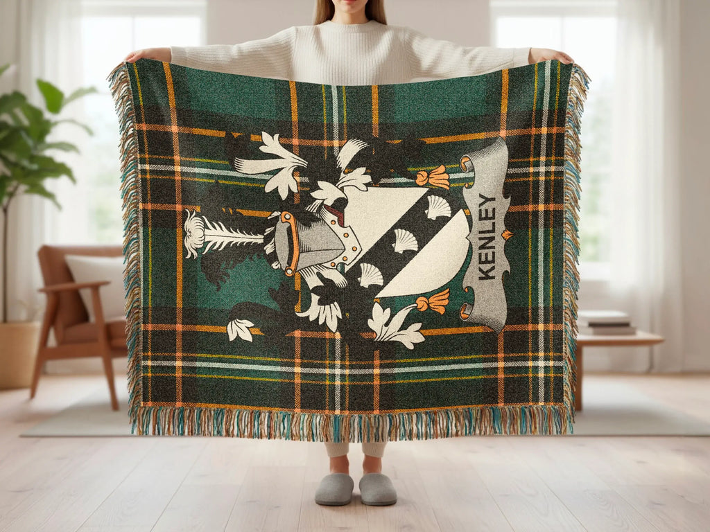 Tartan plaid blanket with crest and "KENLEY" text, held by a person.