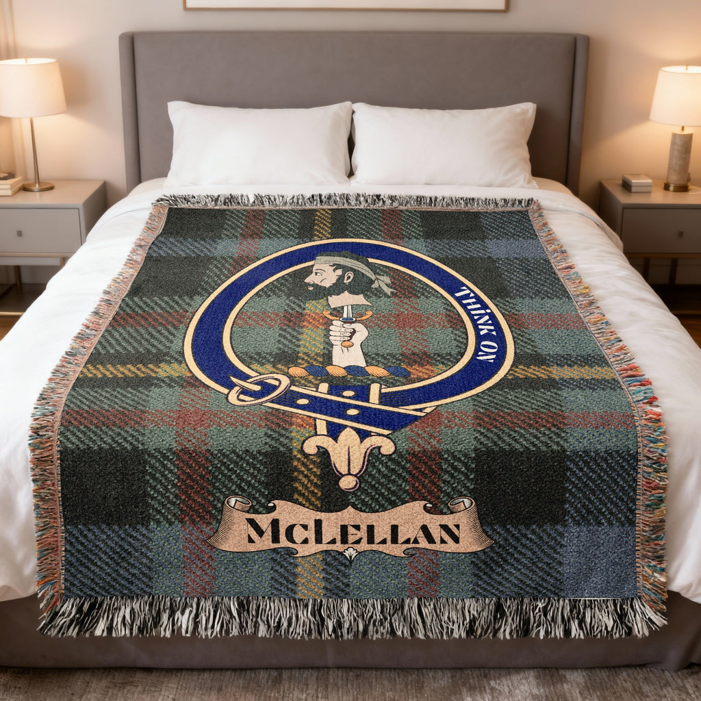 McLellan woven blanket displayed on a bed, with a hand holding a dagger beneath a heraldic head on a green, blue and muted red tartan background