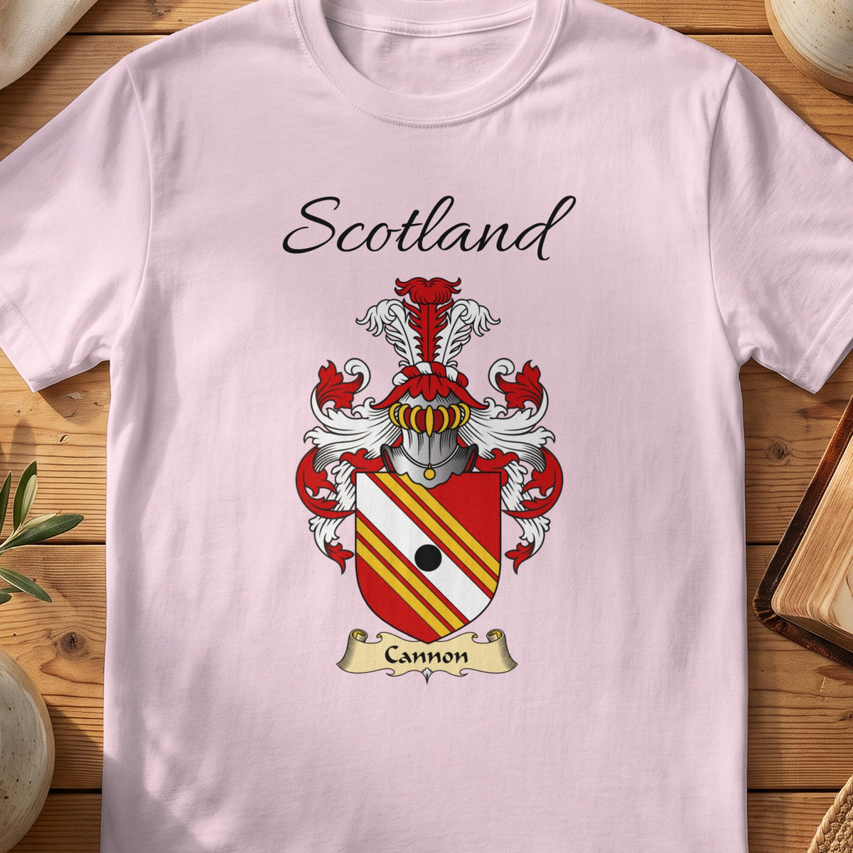 Light Pink Cannon Scottish family shield T-shirt featuring red-and-gold diagonal stripes with a black roundel