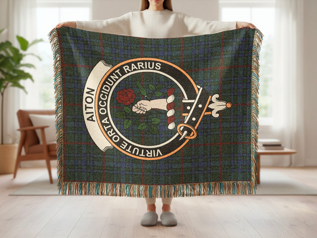 Person holding the Aiton woven blanket to show the full design, tartan background and fringe