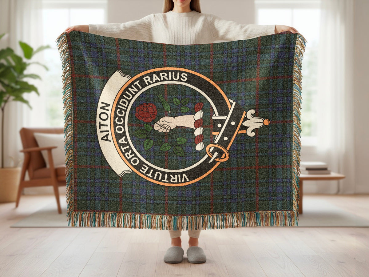 Person holding the Aiton woven blanket to show the full design, tartan background and fringe