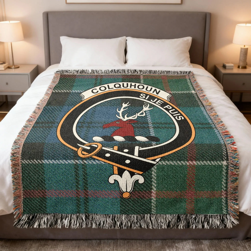 Colquhoun clan tartan woven blanket on sofa — 100% cotton with stag crest and Si Je Puis design