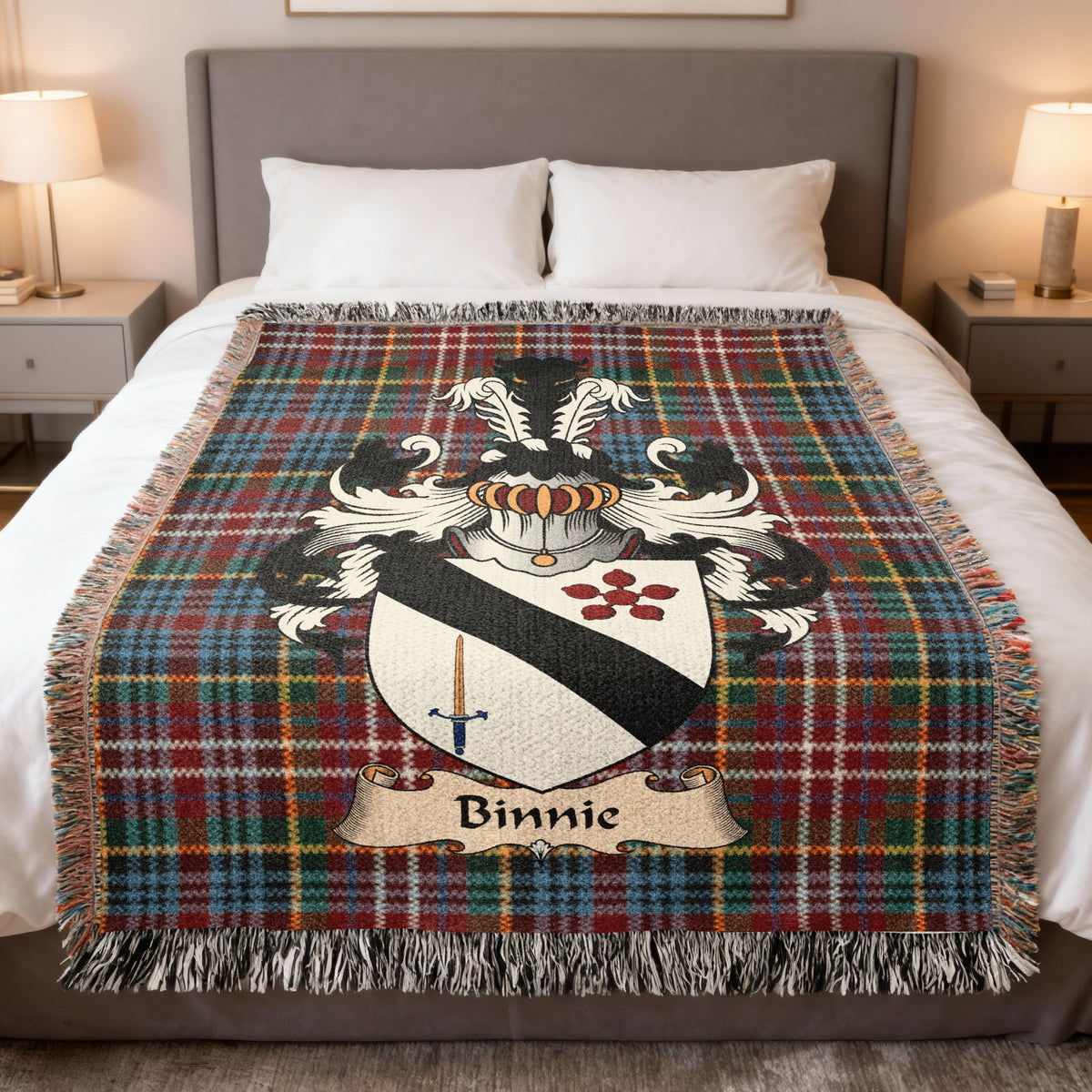 Binnie Scottish family crest woven blanket on a Caledonia tartan background, displayed on a bed