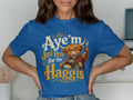 Blue t-shirt with a cartoon Highland cow, fork, and "Aye'm Just Here for the Haggis" text.