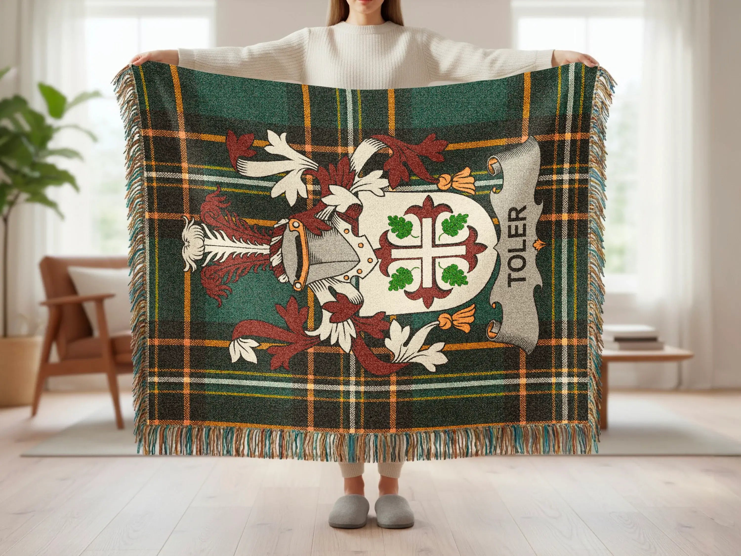 Tartan blanket with shield emblem and "TOLER" text held by a person.