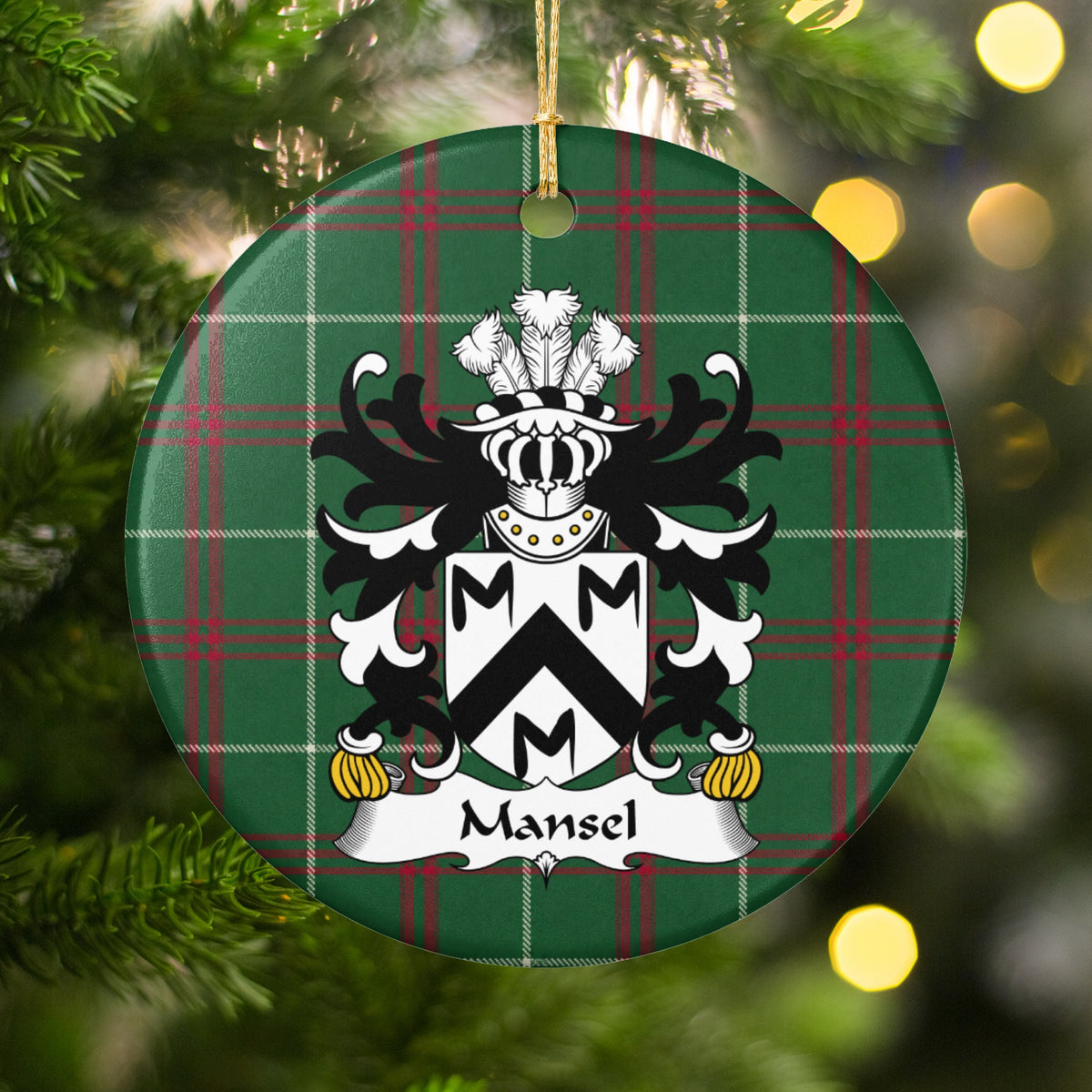 Mansel ornament hanging among Christmas tree branches and warm lights, with a black chevron and three black M-shaped motifs on a white shield on Welsh National Tartan.