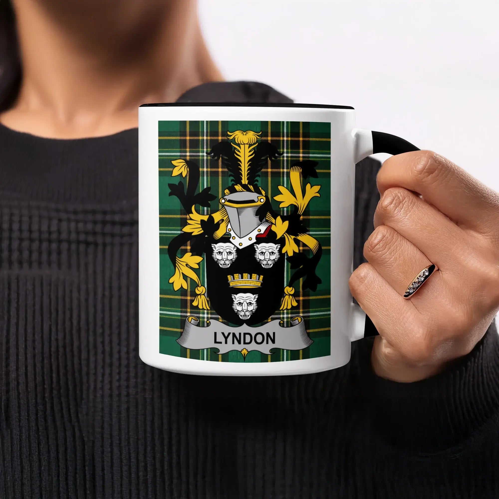 Mug with black handle featuring a green plaid background and the Lyndon coat of arms.