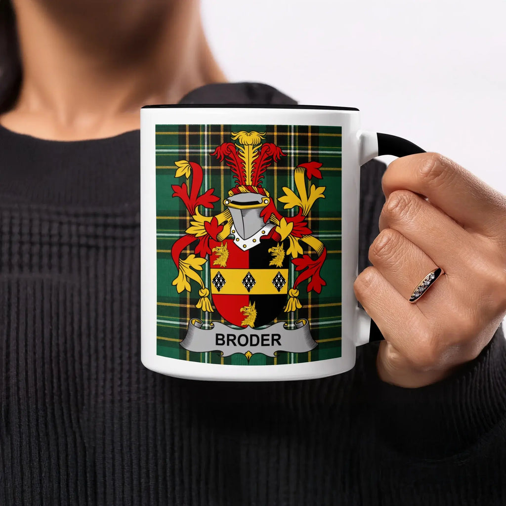 Mug with Broder family crest and tartan background, held by a person.