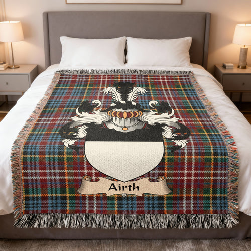 Airth Scottish family crest woven blanket on a Caledonia tartan background, displayed on a bed