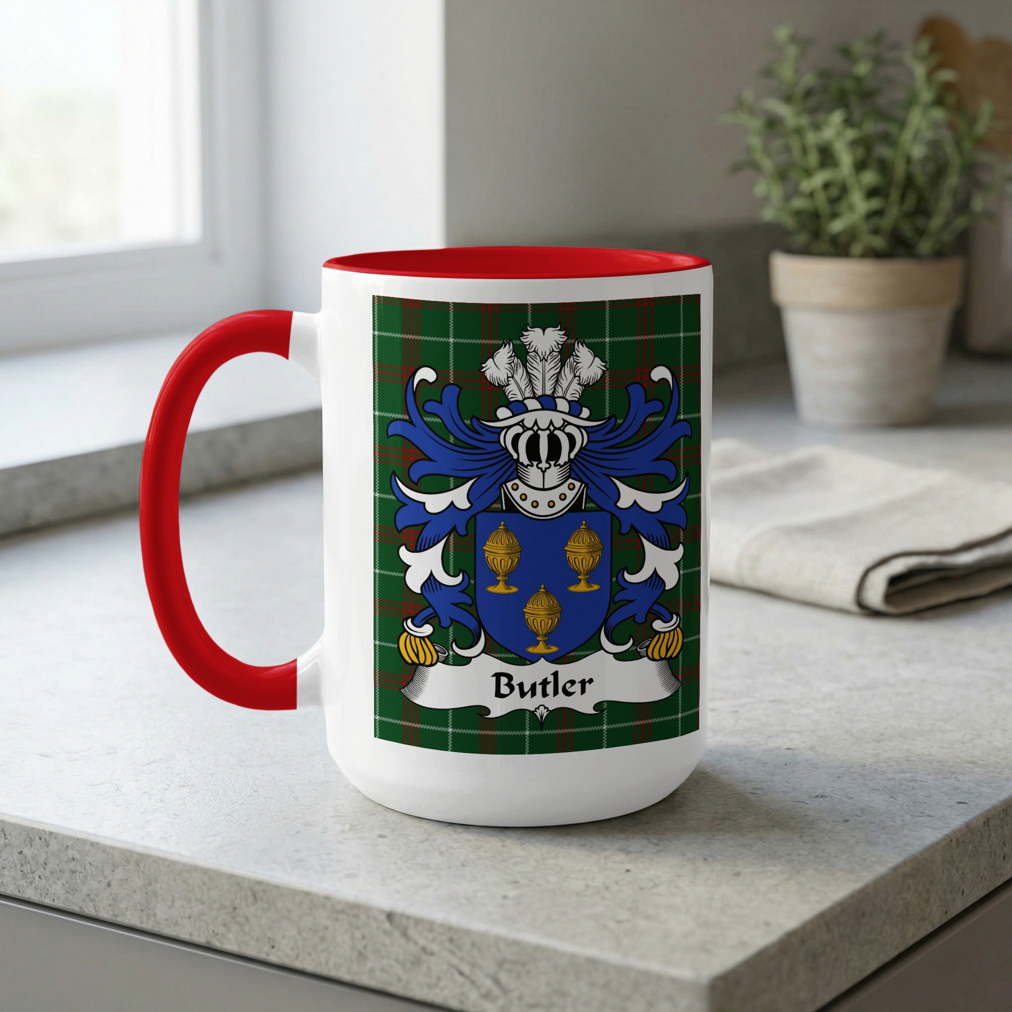 White mug with red handle displaying Butler coat of arms on tartan background.