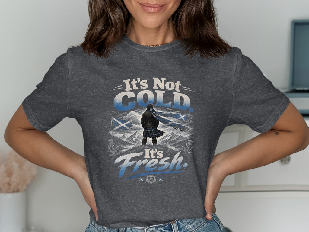 T-shirt graphic with text "It's Not Cold. It's Fresh." featuring a figure in kilt and scarf in a mountainous landscape.