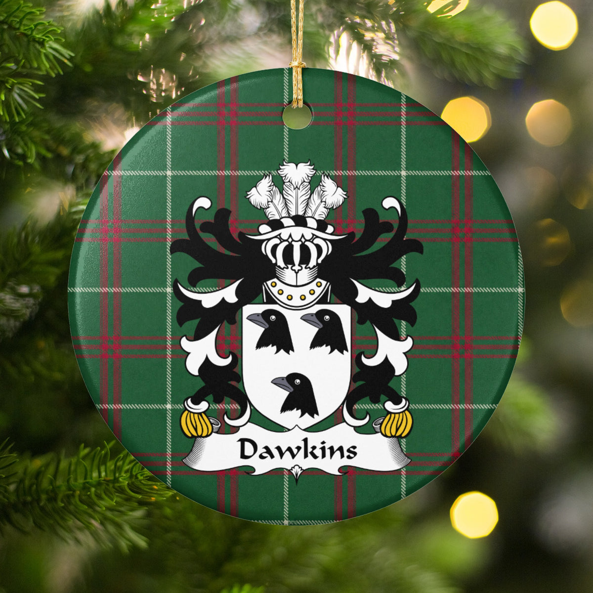 Dawkins ornament hanging among Christmas tree branches and warm lights; three black bird heads on a white shield on Welsh national tartan.