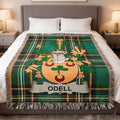 Tartan blanket with Odell family crest draped on a bed.