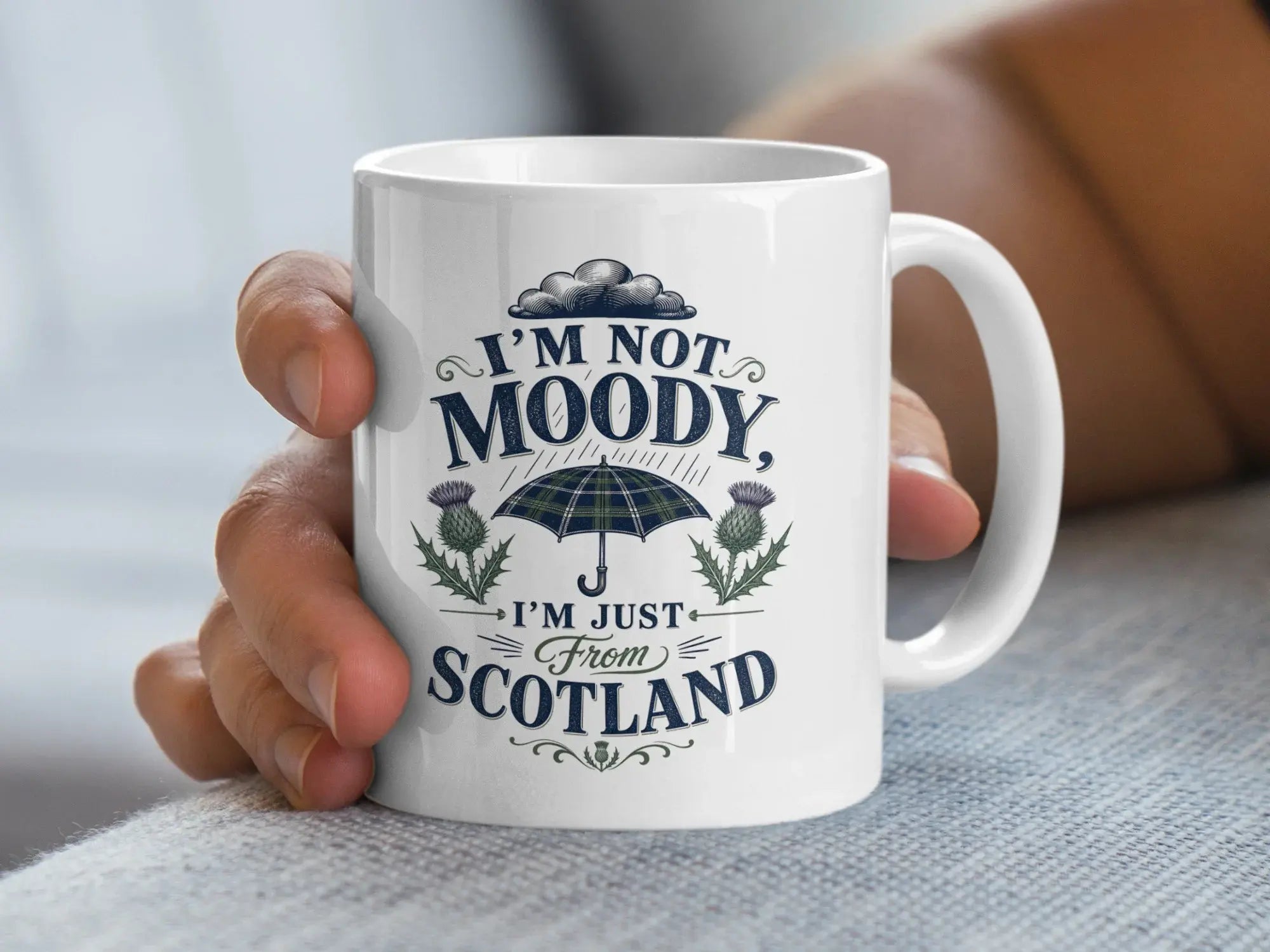 White mug with "I'm not moody, I'm just from Scotland" and plaid umbrella design.