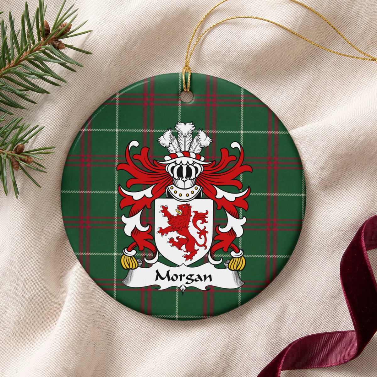 Morgan ornament, Style 1 on cream fabric with gold string, evergreen and burgundy ribbon; a red lion on a white shield on Welsh national tartan.